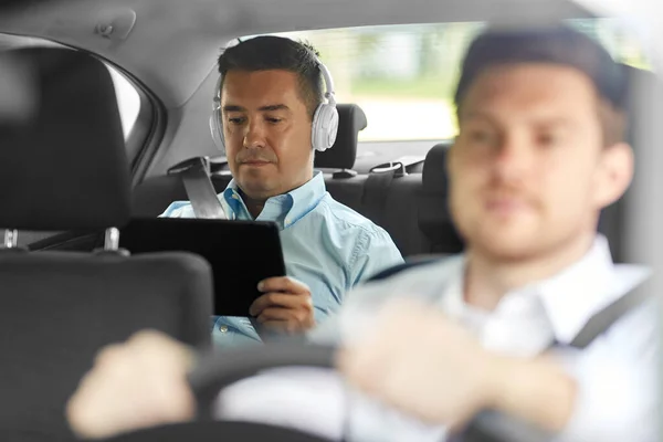 Férfi táblagéppel és fülhallgató lovaglás autóban — Stock Fotó