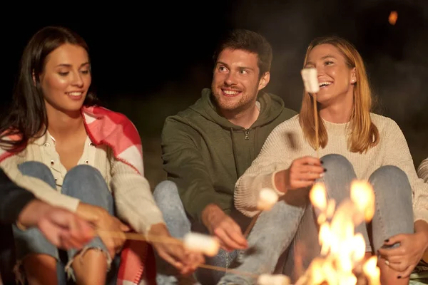 Amigos assar marshmallow no acampamento de fogo à noite — Fotografia de Stock
