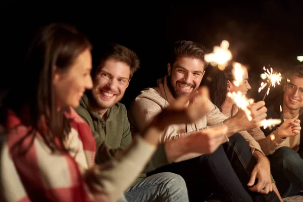 Amigos felizes com faíscas à noite ao ar livre — Fotografia de Stock