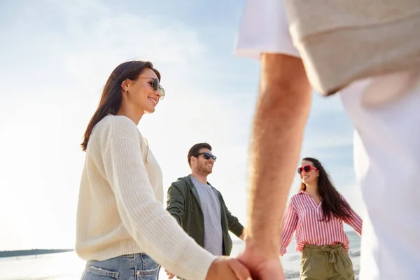 Glada vänner håller varandra i handen på sommarstranden — Stockfoto