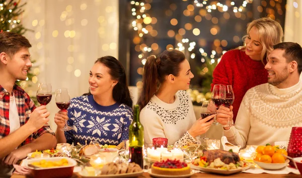 Amigos felizes bebendo vinho tinto na festa de Natal — Fotografia de Stock