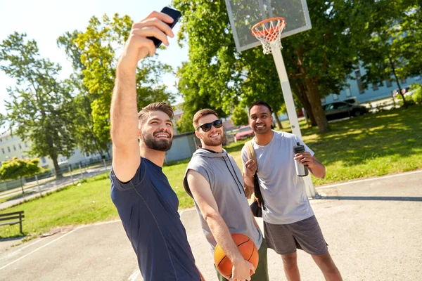 Hommes heureux prenant selfie sur terrain de basket-ball — Photo