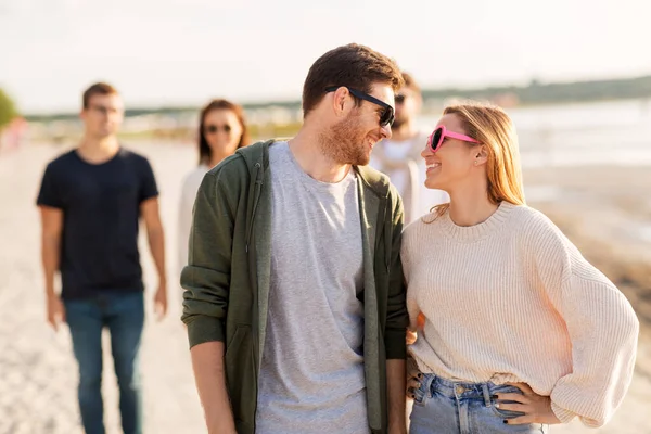 Glada vänner promenader längs sommarstranden — Stockfoto