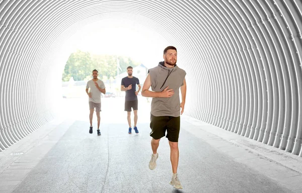 Bărbați tineri sau prieteni de sex masculin alergând în tunel — Fotografie, imagine de stoc