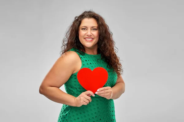 Mulher feliz em vestido verde segurando coração vermelho — Fotografia de Stock