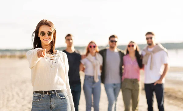 Happy woman with friends on beach pointing to you — Stock Photo, Image