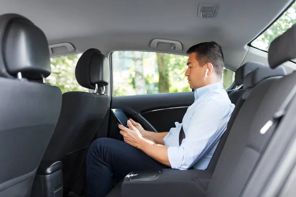 Passageiro com fones de ouvido e tablet pc em táxi carro — Fotografia de Stock