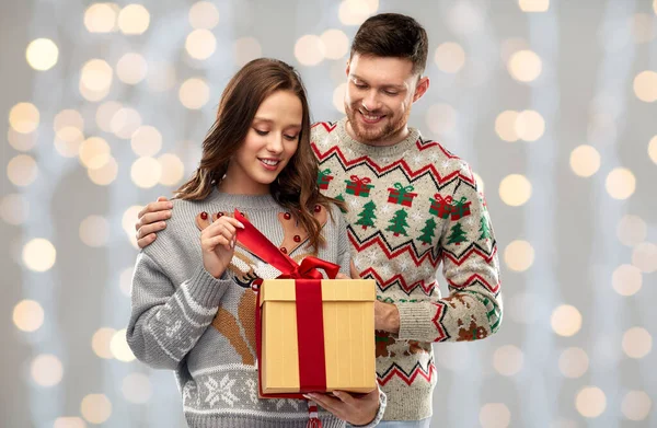 Casal feliz em camisolas de Natal com caixa de presente — Fotografia de Stock