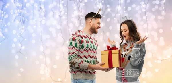 Gelukkig paar in lelijke truien met kerstcadeau — Stockfoto