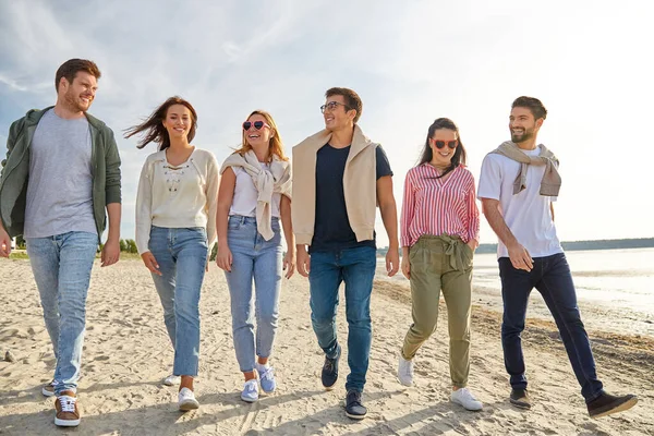 Glada vänner promenader längs sommarstranden — Stockfoto