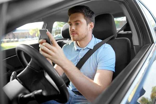 Людина керує автомобілем і використовує смартфон — стокове фото