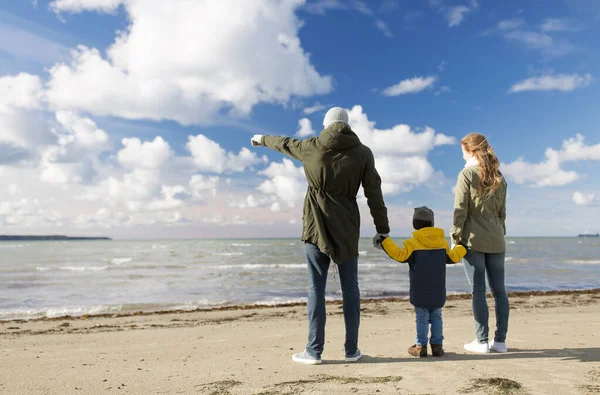 Happy family at autumn beach looking at sea — Stock Photo, Image