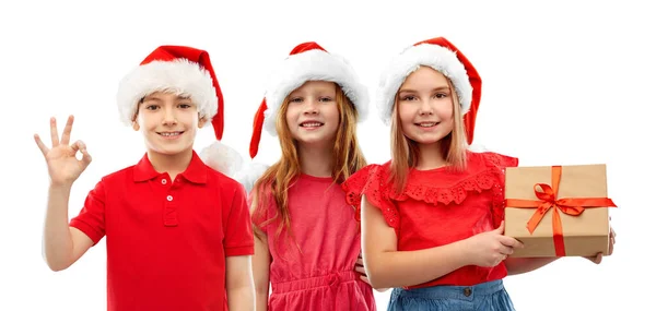 Children in santa helper hats with christmas gift — ストック写真
