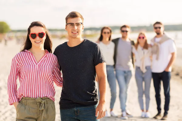 Gelukkige vrienden wandelen langs zomerstrand — Stockfoto