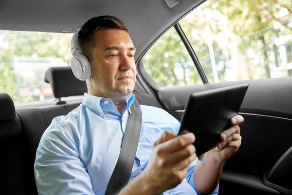 Cestující se sluchátky pomocí tabletu PC v autě Stock Fotografie