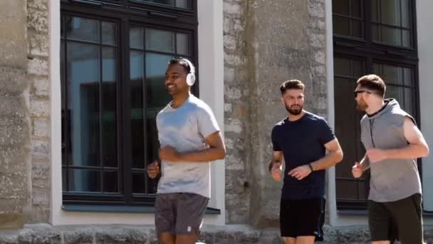 Άνδρες φίλοι με ακουστικά που τρέχουν σε εξωτερικούς χώρους — Αρχείο Βίντεο