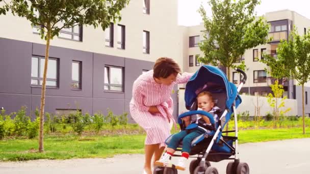 Mamma kysser son äter choklad i barnvagn — Stockvideo