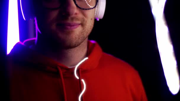 Man in headphones over neon lights of night club — Stock Video