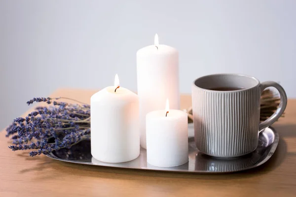 Velas, té en taza y flores de lavanda en la mesa —  Fotos de Stock