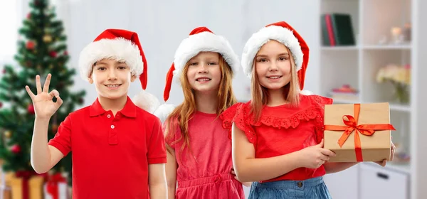 Niños en sombreros de ayudante de santa con regalo de Navidad —  Fotos de Stock