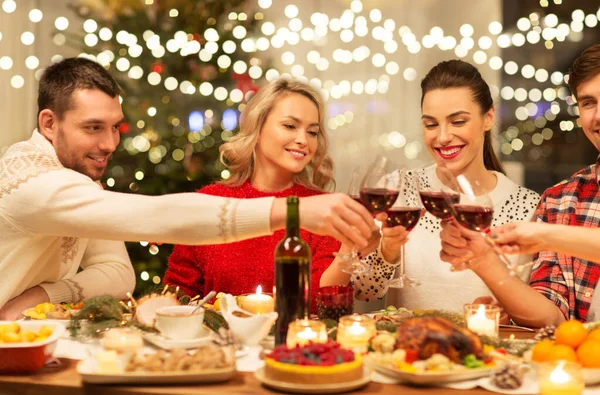 Glada vänner dricker rött vin på julfesten — Stockfoto