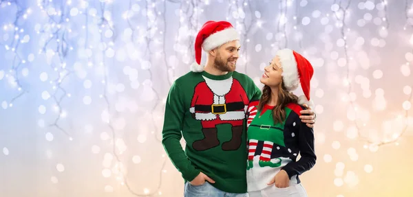 Casal feliz em camisolas de Natal e chapéus de santa — Fotografia de Stock