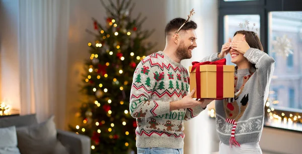 Šťastný pár v vánoční svetry s dárkovou krabičkou — Stock fotografie