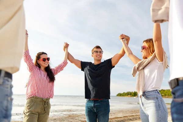 Szczęśliwy przyjaciele trzymając się za ręce na letniej plaży — Zdjęcie stockowe