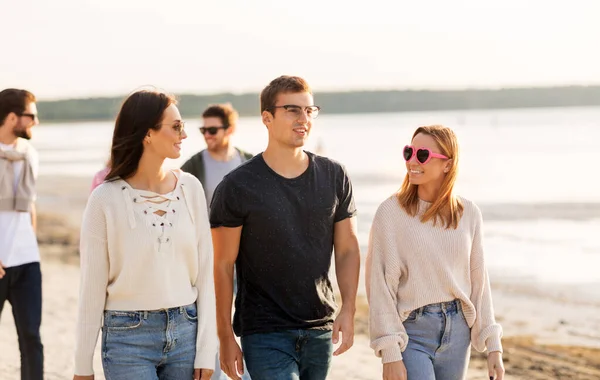 Gelukkige vrienden wandelen langs zomerstrand — Stockfoto