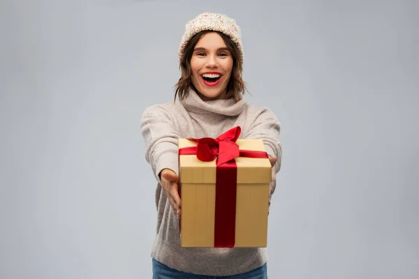 Νεαρή γυναίκα σε πλεκτό καπέλο χειμώνα κρατώντας κουτί δώρου — Φωτογραφία Αρχείου