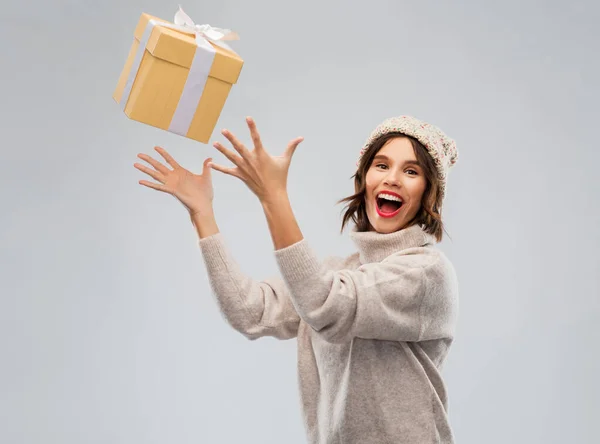 Mujer joven en invierno sombrero captura caja de regalo —  Fotos de Stock