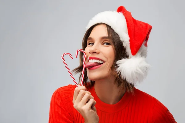 Vrouw in santa hoed likt snoep stokken op kerst — Stockfoto