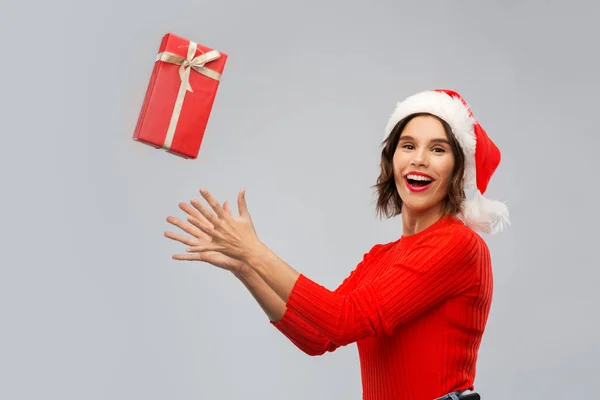 Glückliche junge Frau mit Weihnachtsmannhut fängt Geschenkbox — Stockfoto