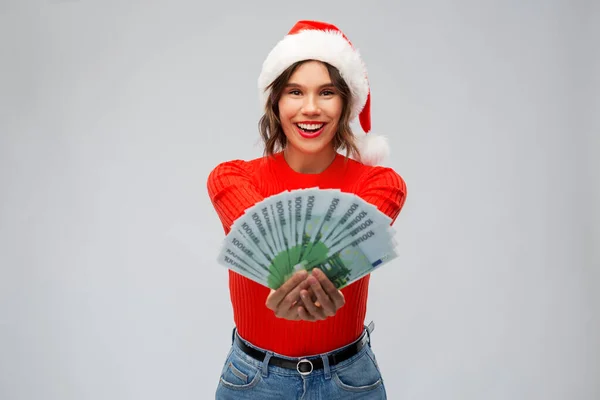 Happy woman in santa hat with money on christmas — Stock Photo, Image