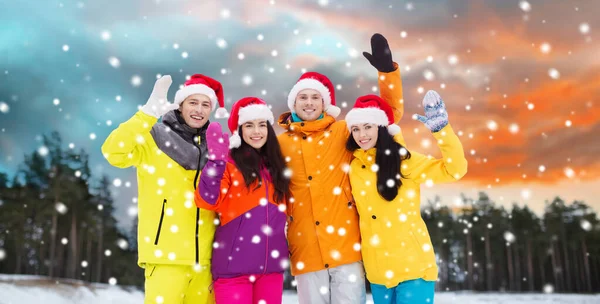 Amigos felices en sombreros de santa y trajes de esquí al aire libre —  Fotos de Stock