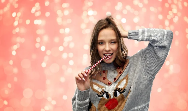 Woman in christmas sweater biting candy cane — Stock Photo, Image