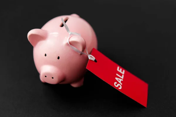 piggy bank with red sale tag on black