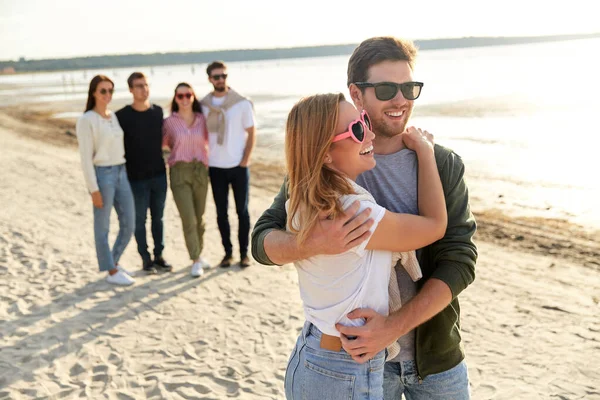 Gelukkig paar en groep vrienden op zomerstrand — Stockfoto