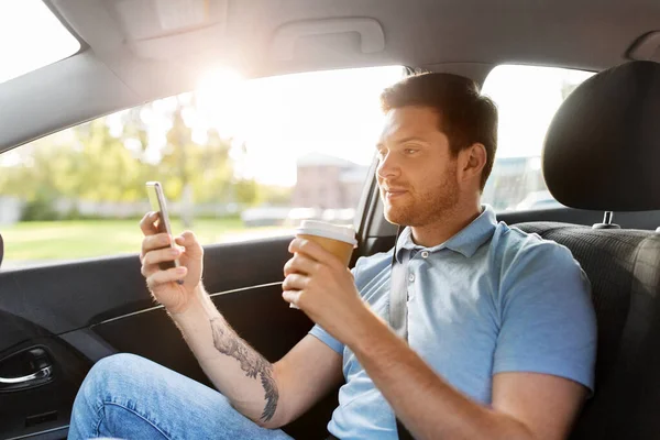 Passageiro beber café usando smartphone no carro — Fotografia de Stock