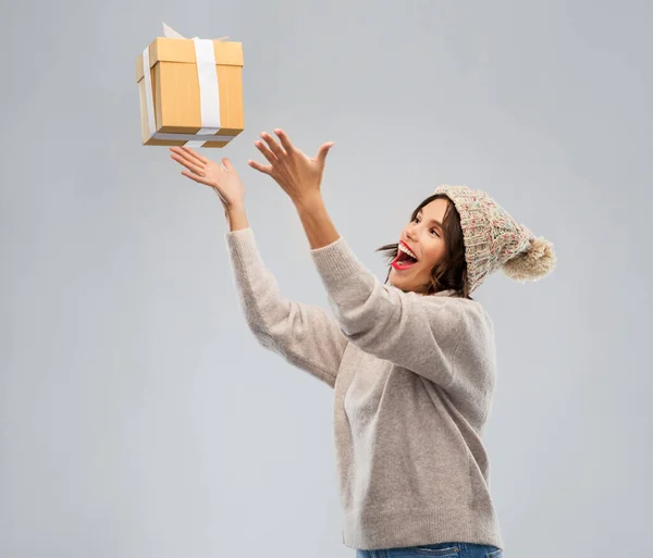 Νεαρή γυναίκα σε χειμερινό καπέλο αλίευση κουτί δώρου — Φωτογραφία Αρχείου