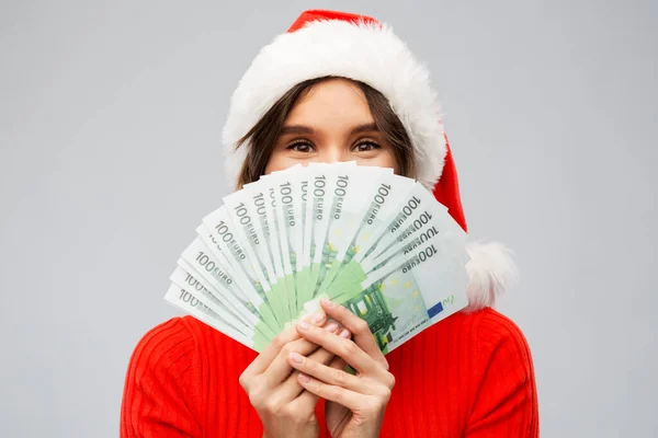 Happy woman in santa hat with money on christmas — Stock Photo, Image