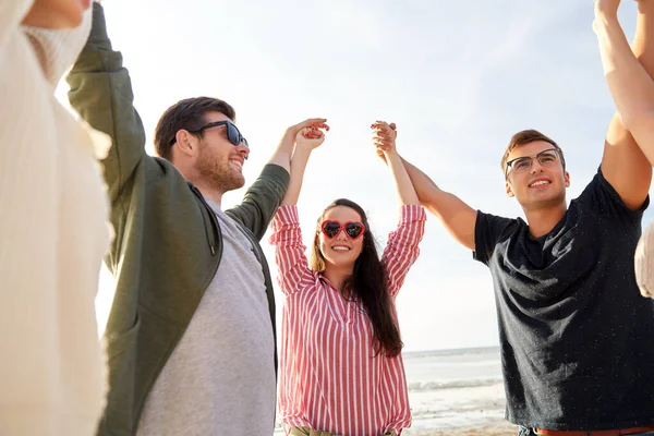 Glückliche Freunde halten Händchen am Sommerstrand — Stockfoto