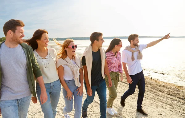 Amigos felizes andando ao longo da praia de verão — Fotografia de Stock