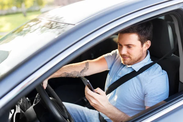 Homem dirigindo carro e usando smartphone — Fotografia de Stock