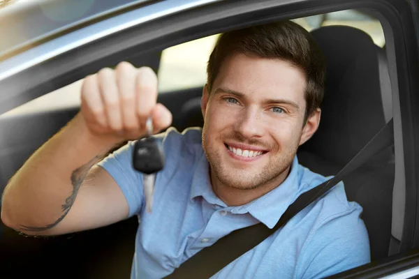 Sorridente homem ou motorista com chave sentado no carro — Fotografia de Stock