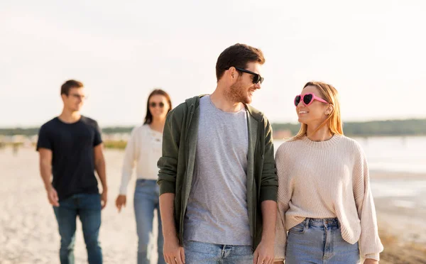 Amici felici passeggiando lungo la spiaggia estiva — Foto Stock