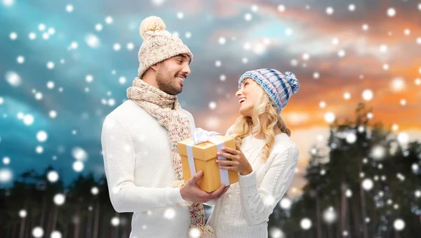 Pareja sonriente en ropa de invierno con caja de regalo —  Fotos de Stock