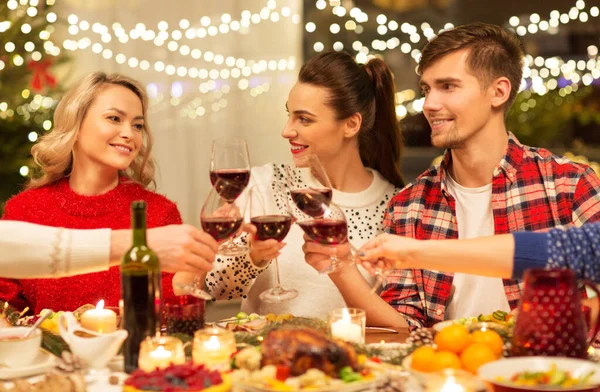 Gelukkig vrienden drinken rode wijn op kerstfeest — Stockfoto