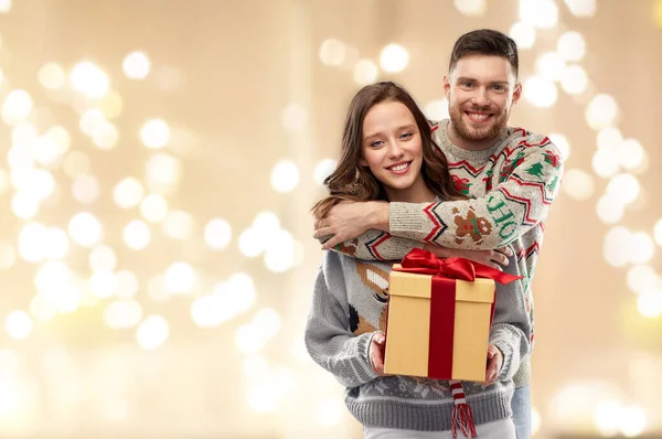Glückliches Paar in Weihnachtspullis mit Geschenkbox — Stockfoto