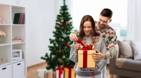 Casal feliz em camisolas de Natal com caixa de presente — Fotografia de Stock